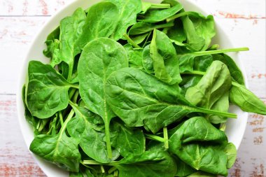 Sağlıklı yiyecekler, sebzeler, büyük beyaz bir kasede taze ıspanak yaprakları. Zirve görünümü.