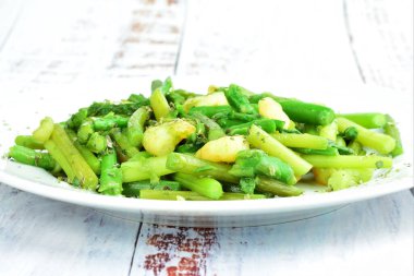 Kapatın. Beyaz bir tabakta servis edilen karidesli kuşkonmaz, baharat, kekik ve zeytinyağı. Boşluğu kopyala.