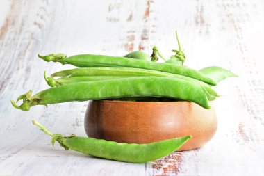 Kapatın. Bezelyeler ahşap bir kasede, açık renkli bir masada, boşluğu kopyalayın..