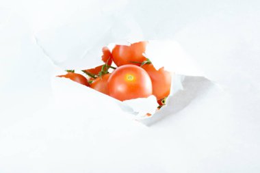 Beyaz yapraklı merkezi açılış. Kapatın. Taze ve yararlı küçük domatesler. Beyaz arka plan. Kavram, sağlıklı yemek, zihnini aç..