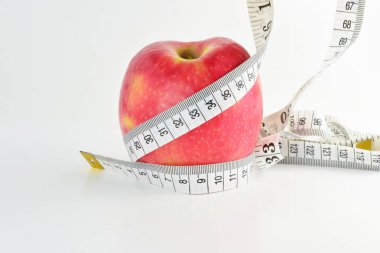 Ölçüm bandı olan kırmızı elma, beyaz arka planda izole edilmiş. Kavram, sağlıklı beslenme, sırayı bozmayın..