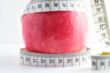 Yaklaş, kırmızı elma, ölçüm bandıyla, beyaz arka planda izole edilmiş. Kavram, sağlıklı beslenme, sırayı bozmayın..