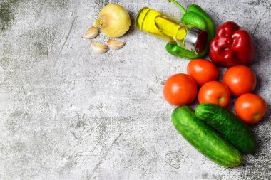 Çeşitli sebzeler, zeytinyağı, domatesler, sarımsak ve soğanlar, büyük beslenme erdemleriyle, hepsi kopya alanı olan taştan bir arka planda..