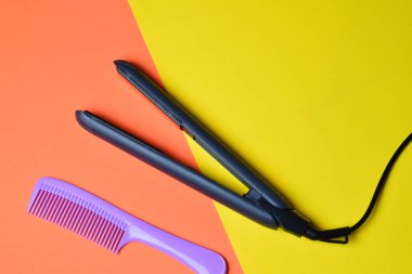 İzole edilmiş seramik plakalı saç düzleştirici uzun taraklı, çift renkli arka plan. Boşluğu kopyala.