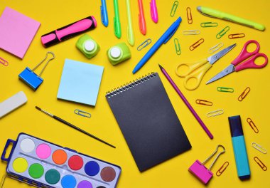 Sarı arka planda çeşitli okul aksesuarları, zirve manzarası.