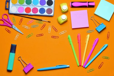 Turuncu arka planda okul malzemeleri, kopyalama alanı ve genel görünüm.