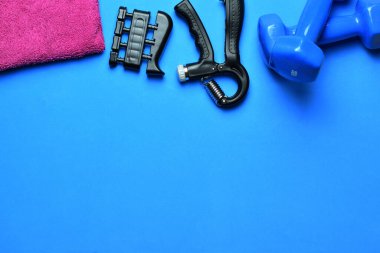 Manüel eğitim tutuşu, dambıllar ve çeşitli aksesuarlar, mavi arka planda. Zirve görünümü ve boşluk kopyala.