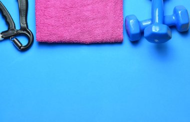 Manüel eğitim tutuşu, dambıllar ve çeşitli aksesuarlar, mavi arka planda. Zirve görünümü ve boşluk kopyala.