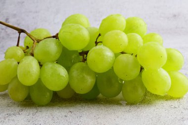 Beyaz üzümler, taştan arka planda gri tonlarda..