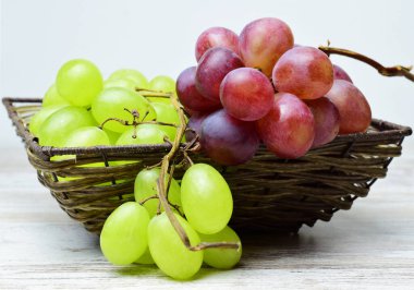 Üzüm çeşitliliği, hasır sepette demet ve hafif ahşap taban.