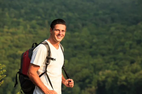 Ein lächelnder Mann mit Rucksack auf dem Rücken der Natur — Stockfoto