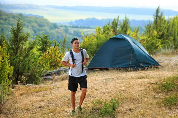 Uomo attico con zaino e tenda in piedi sullo sfondo della natura — Foto Stock