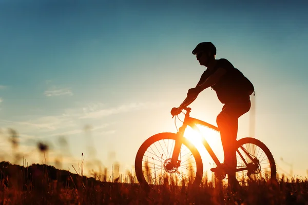 Rowerzysta człowiek z rowerem na zachód słońca — Zdjęcie stockowe