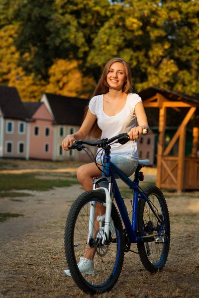 Jovem linda senhora posando em uma bicicleta no parque — Fotografia de Stock