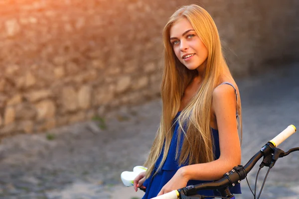 Jovem senhora bonito posando em uma bicicleta perto da parede — Fotografia de Stock
