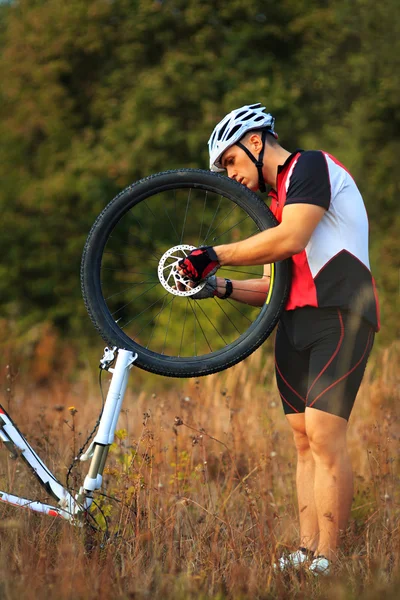 Ciclista repara bicicleta en el prado —  Fotos de Stock