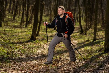 Erkek yürüyüşçü ormanda yürürken yan tarafa bakıyor.