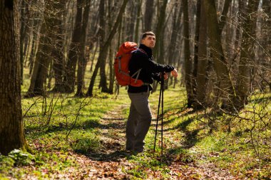 Erkek yürüyüşçü ormanda yürürken yan tarafa bakıyor.