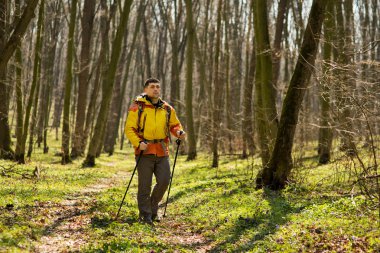 Erkek yürüyüşçü ormanda yürürken yan tarafa bakıyor.
