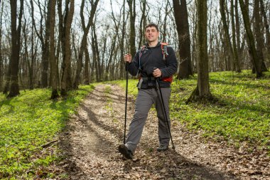 Erkek yürüyüşçü ormanda yürürken yan tarafa bakıyor.