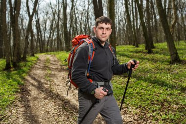 Erkek yürüyüşçü ormanda yürürken yan tarafa bakıyor.