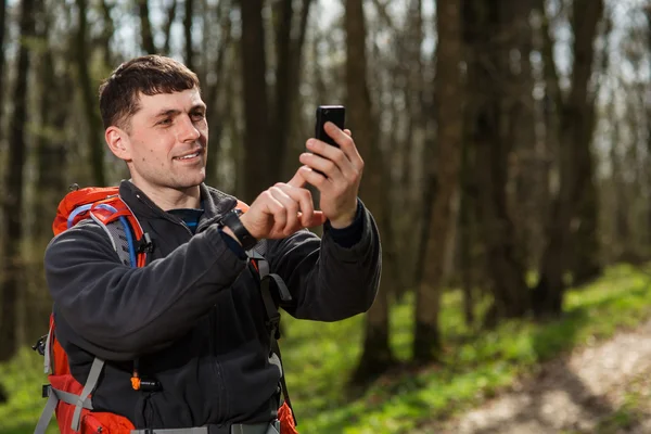 Hombre excursionista tomando fotos con teléfono inteligente en el bosque — Foto de Stock