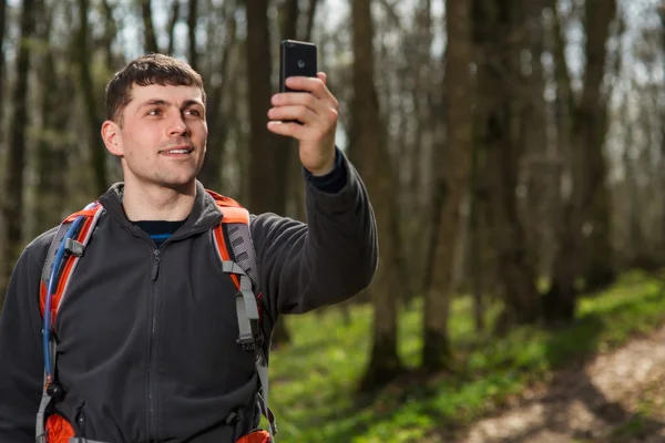 Hombre excursionista tomando fotos con teléfono inteligente en el bosque — Foto de Stock