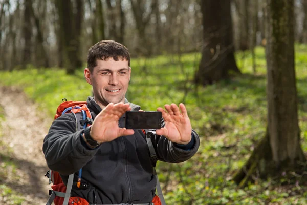 Hombre excursionista tomando fotos con teléfono inteligente en el bosque — Foto de Stock