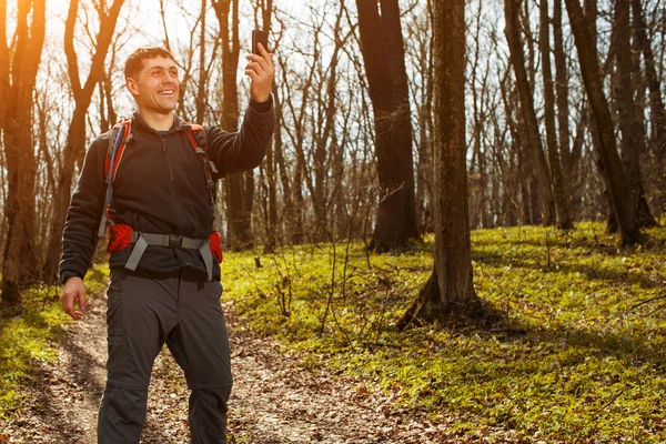 Человек турист фотографируется со смартфоном в лесу — стоковое фото