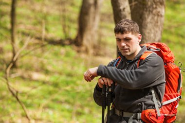 Erkek yürüyüşçü ormanda yürürken yan tarafa bakıyor.