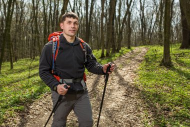 Erkek yürüyüşçü ormanda yürürken yan tarafa bakıyor.