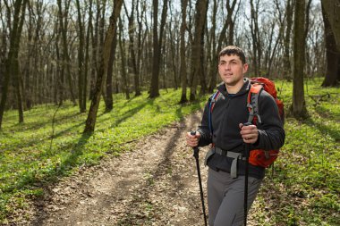 Erkek yürüyüşçü ormanda yürürken yan tarafa bakıyor.