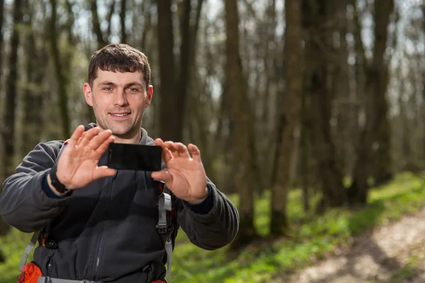Hombre excursionista tomando fotos con teléfono inteligente en el bosque — Foto de Stock