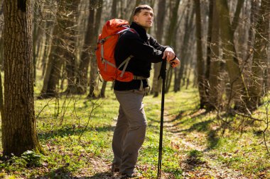 Erkek yürüyüşçü ormanda yürürken yan tarafa bakıyor.