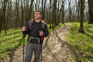 Erkek yürüyüşçü ormanda yürürken yan tarafa bakıyor.