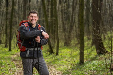 Erkek yürüyüşçü ormanda yürürken yan tarafa bakıyor.