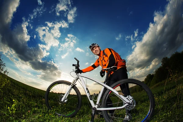 Biker i orange jersey ridning på gröna sommaren sätter — Stockfoto