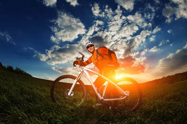 Homem ciclista com bicicleta no pôr do sol — Fotografia de Stock