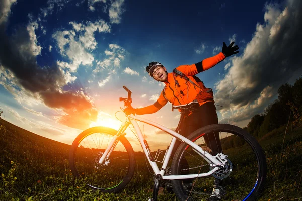 Homem ciclista com bicicleta no pôr do sol — Fotografia de Stock