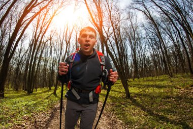 Erkek yürüyüşçü ormanda yürürken yan tarafa bakıyor.