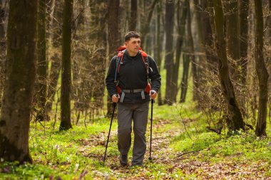 Erkek yürüyüşçü ormanda yürürken yan tarafa bakıyor.