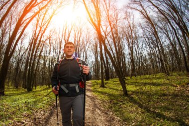Erkek yürüyüşçü ormanda yürürken yan tarafa bakıyor.