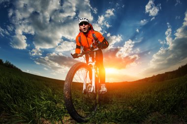 wide angle portrait against blue sky of mountain biker Cyclist clipart