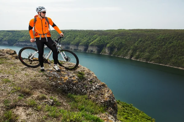 Ciclista en Orange Wear Montar en bicicleta por encima del río — Foto de Stock