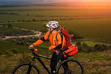 Genç adam yeşil çayır kırsal bir yolda Bisiklete binme