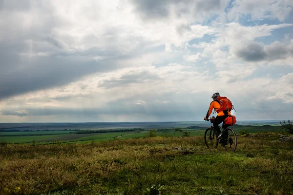 Genç adam yeşil çayır kırsal bir yolda Bisiklete binme