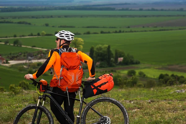 Jongeman fietsen op een landelijke weg via de groene weide — Stockfoto