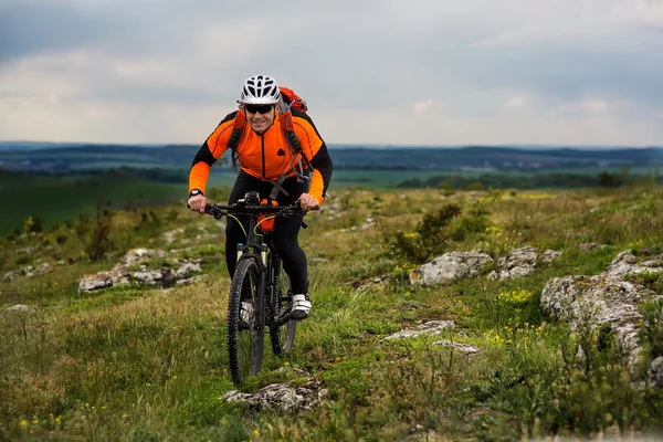 Jongeman fietsen op een landelijke weg via de groene weide — Stockfoto