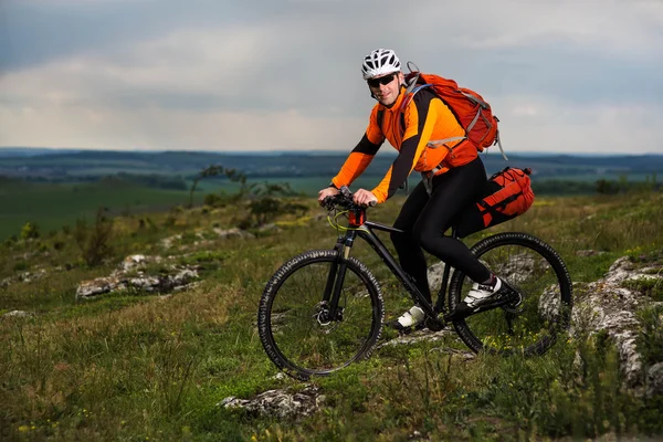 Joven ciclismo en un camino rural a través del prado verde — Foto de Stock