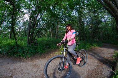 Genç kadın parkta Bisiklete binmek eğleniyor.